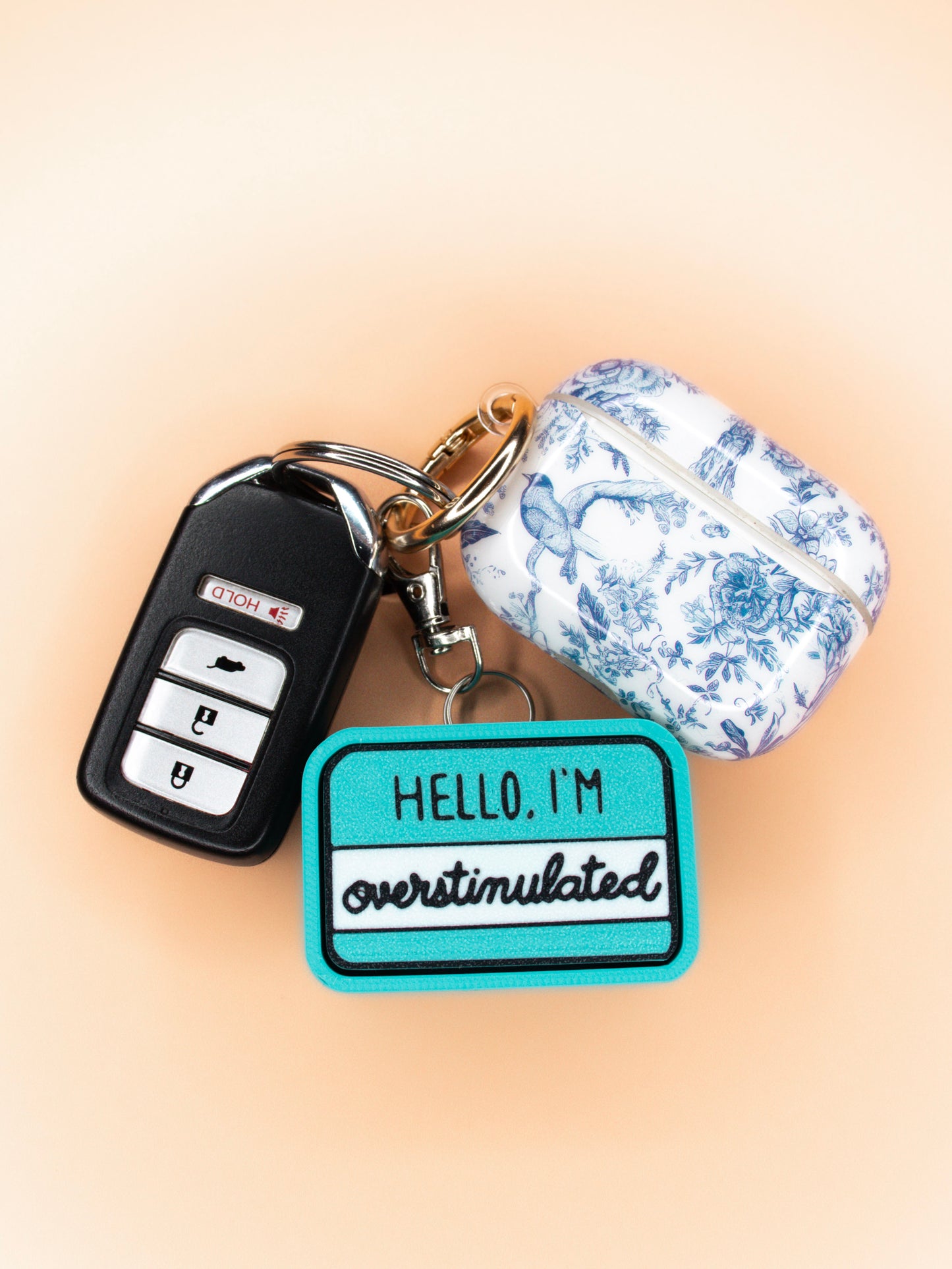 Hello I'm overstimulated clicky keychain top view on set of keys on orange background