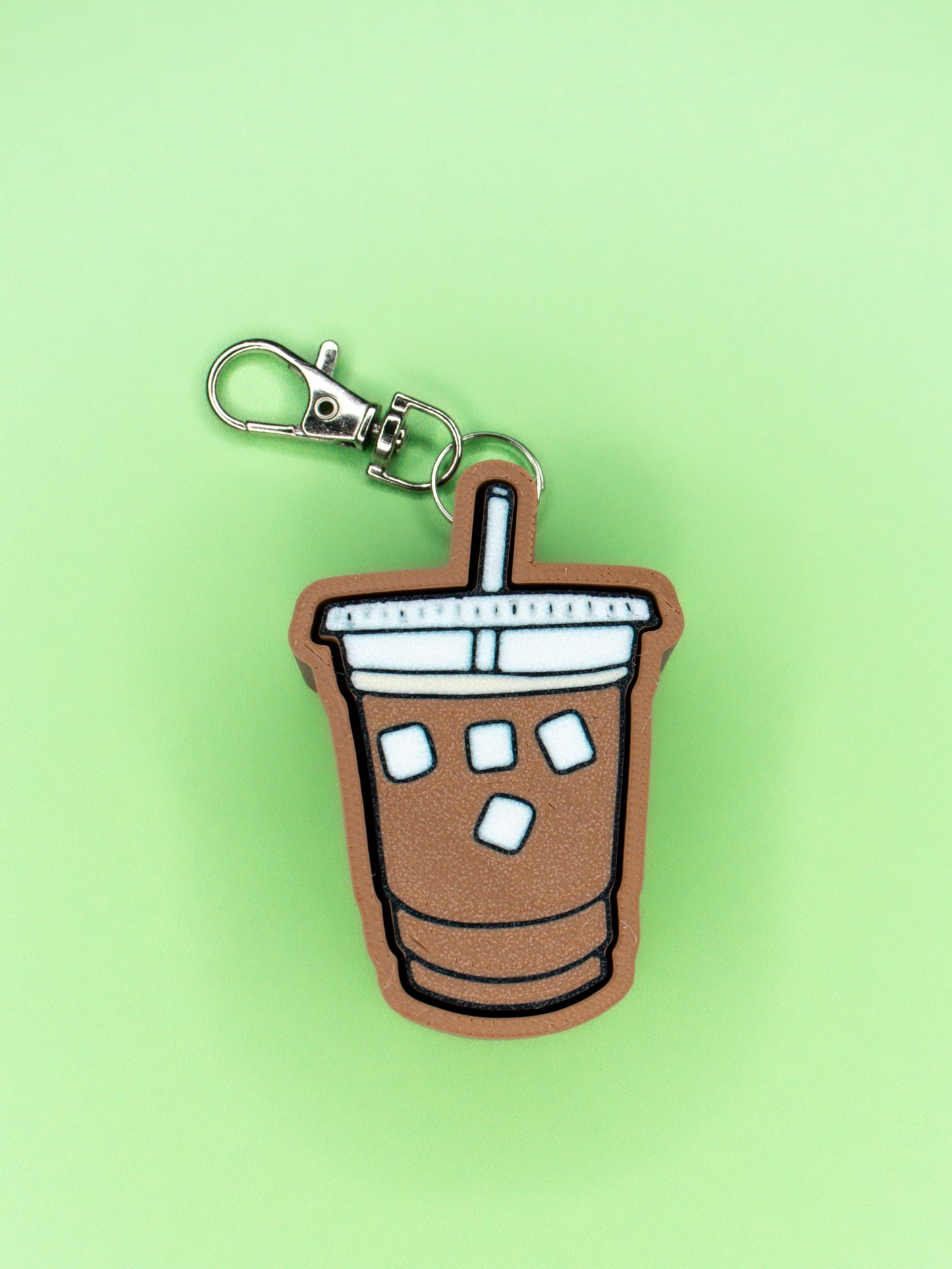 Iced Coffee Clicky Keychain top view laying on green background