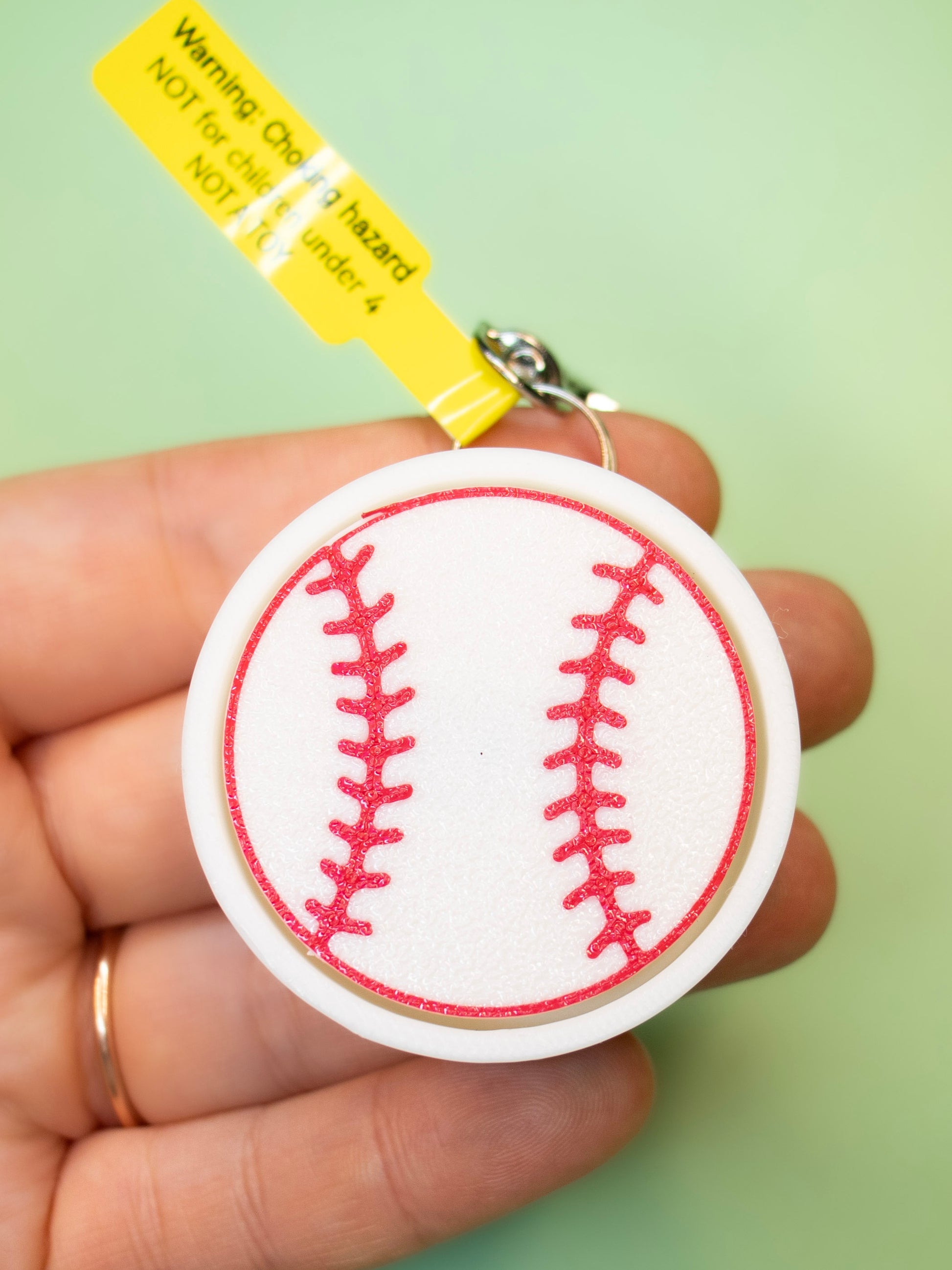 Baseball Keychain in hand on green background