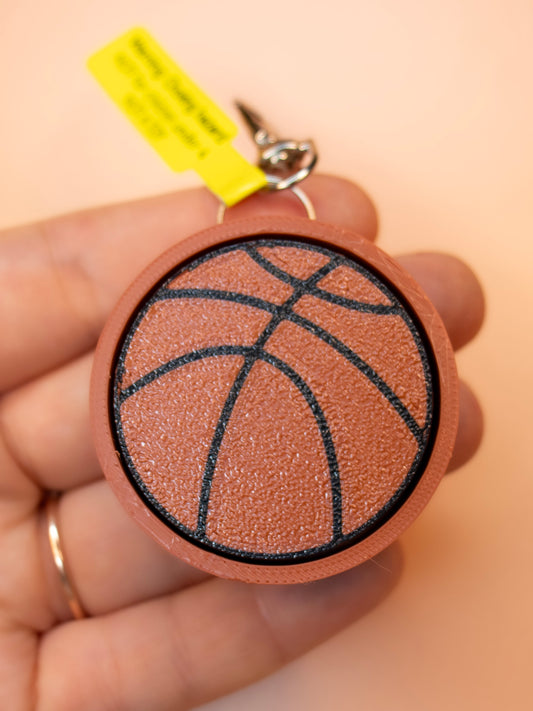 Basketball clicky keychain in hand with orange background