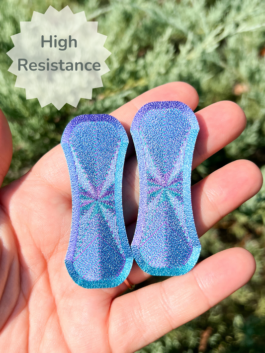 Blue glittery colored high resistance magnetic fidget slider in hand with a greenery background