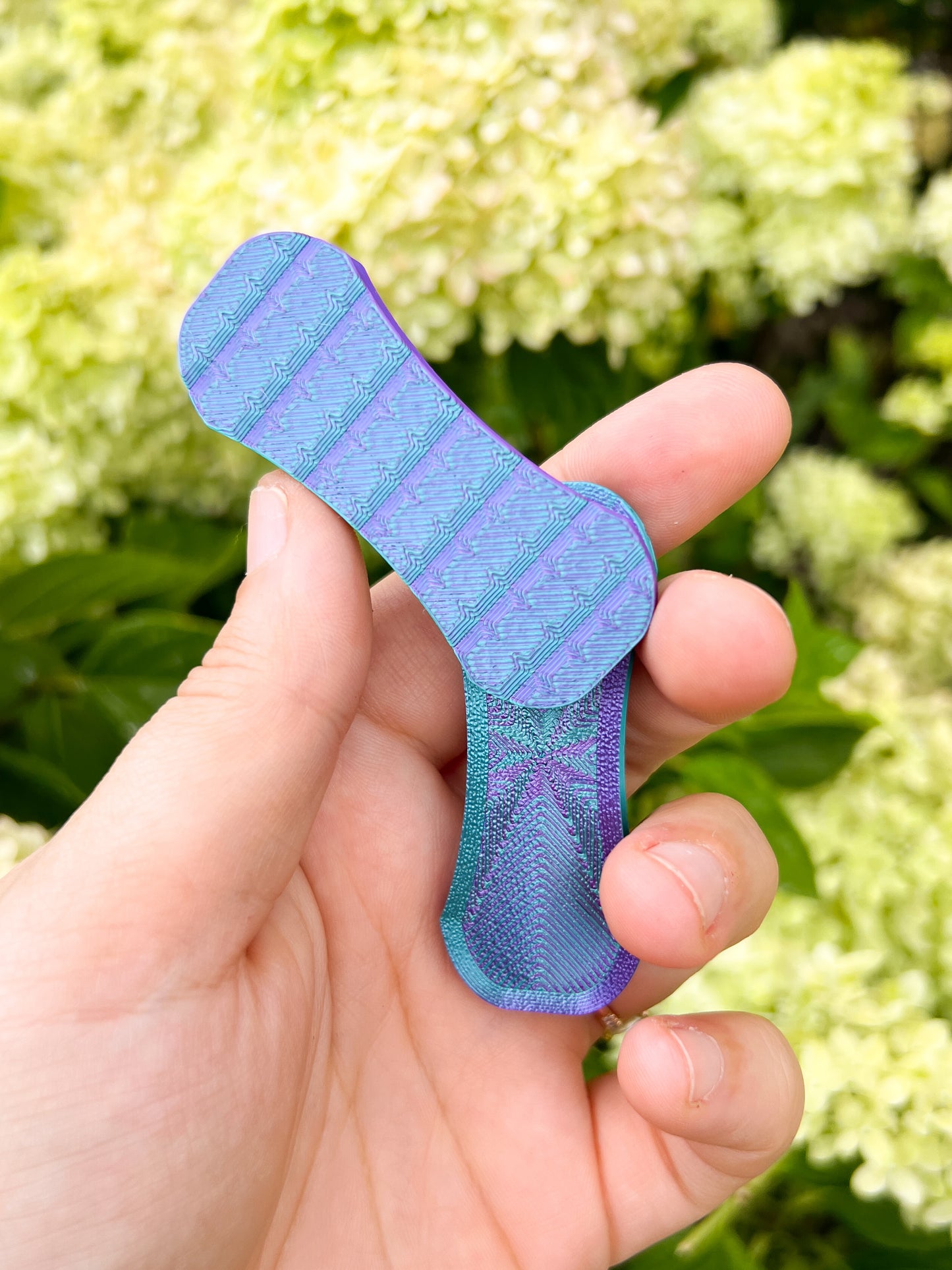 Teal and puruple magnetic fidget slider in hands floral background