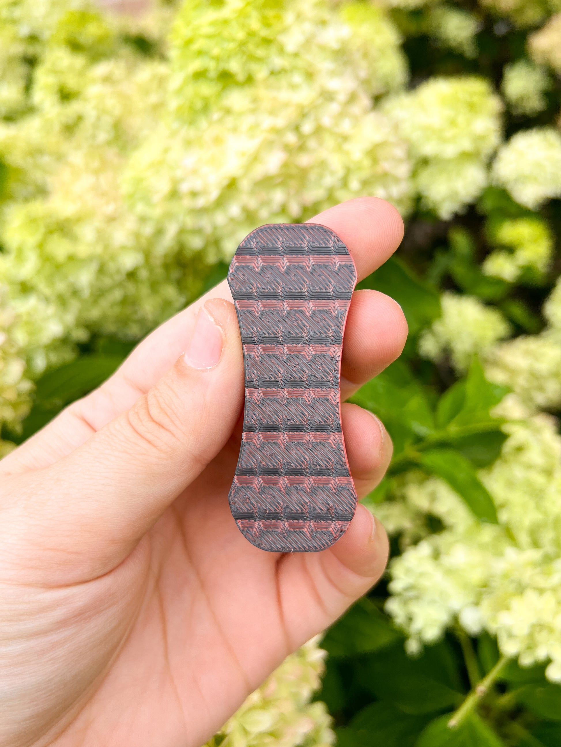 Black and red magnetic fidget slider in hand floral background