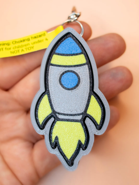 Rocketship clicky keychain in hand and orange background